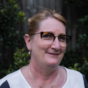 Photo of Maria Thompson smiling and in front of a tree-filled background